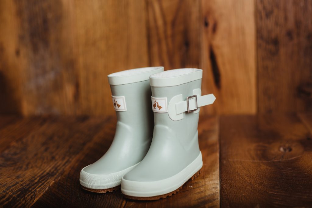  Goose and gander waterproof kids puddle duck wellies in a sage on a brown wooden backdrop.